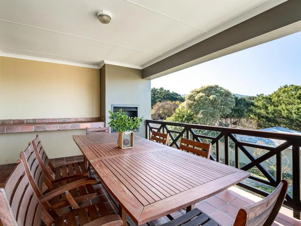 Wooden deck with dining table and chairs overlooking forested landscape
