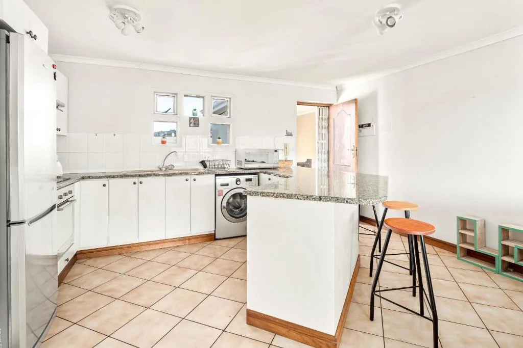 Bright white kitchen with granite countertops, appliances, and breakfast bar seating