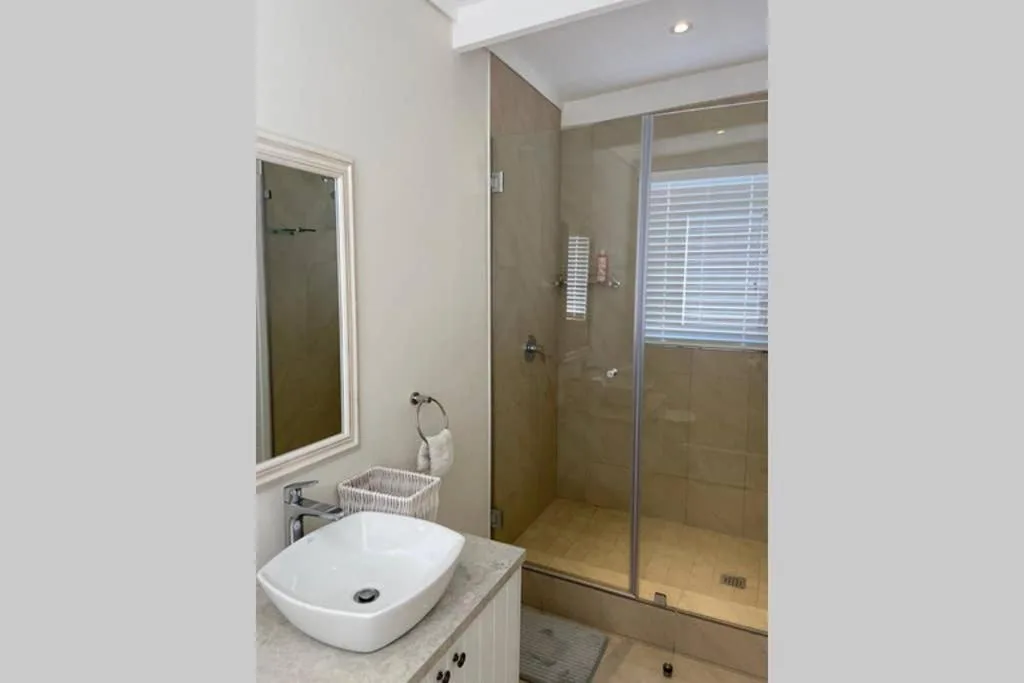 Modern bathroom with vessel sink, large mirror, and walk-in shower enclosure