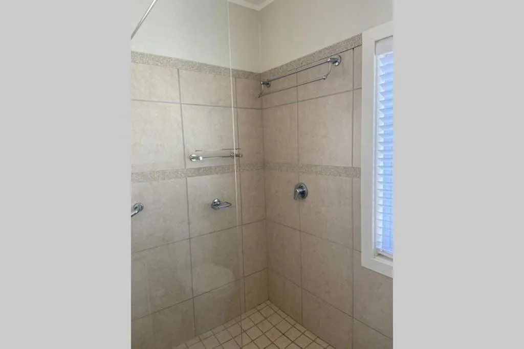 Spacious walk-in shower with glass enclosure and neutral tile walls
