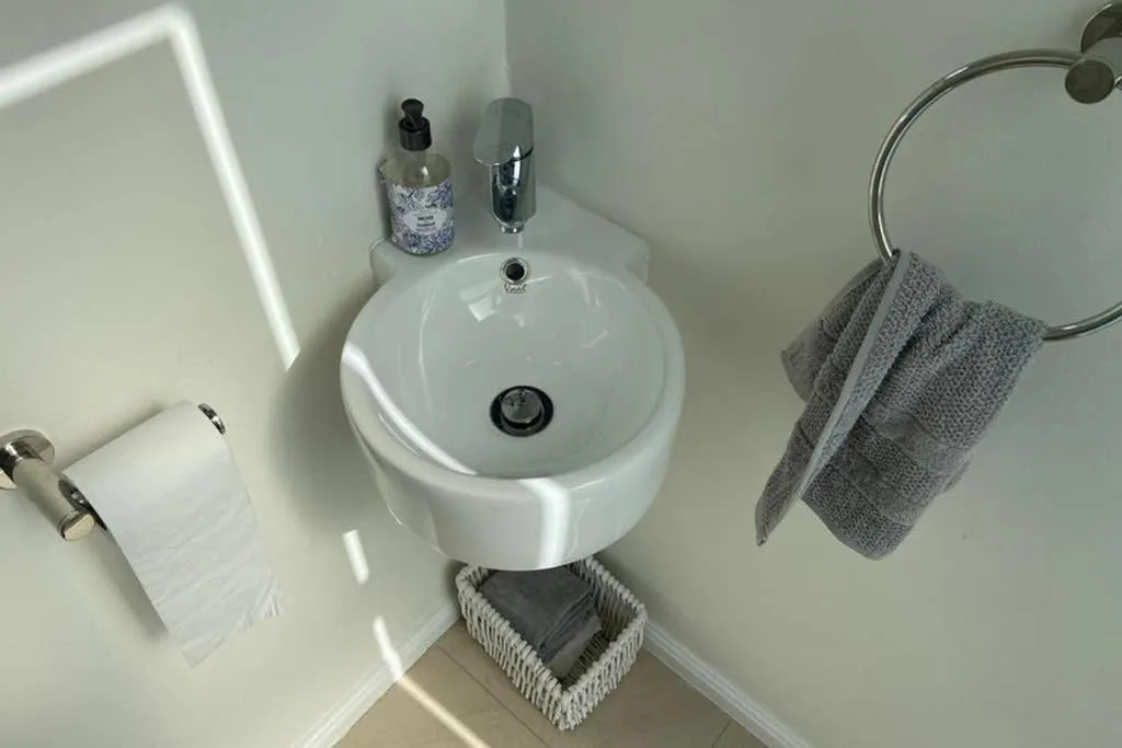 Modern white circular sink with chrome fixtures and gray towels
