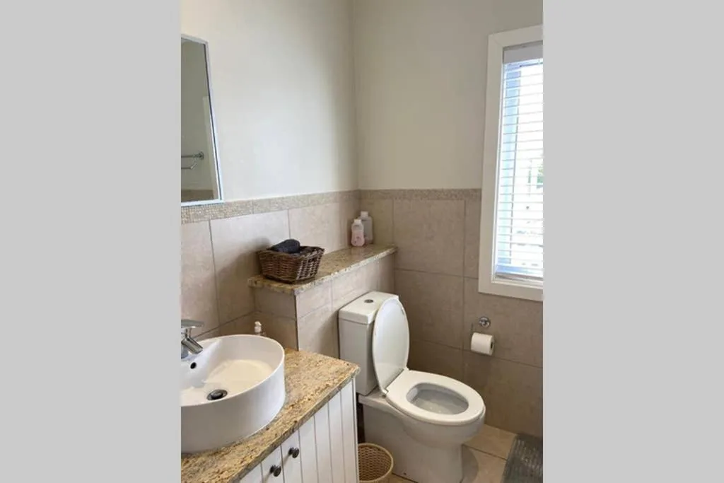Clean bathroom with round sink, toilet, and granite countertop vanity