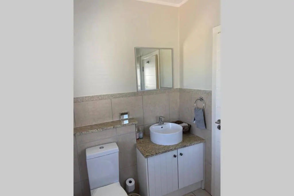 Modern bathroom with round white sink, vanity, toilet, and large mirror