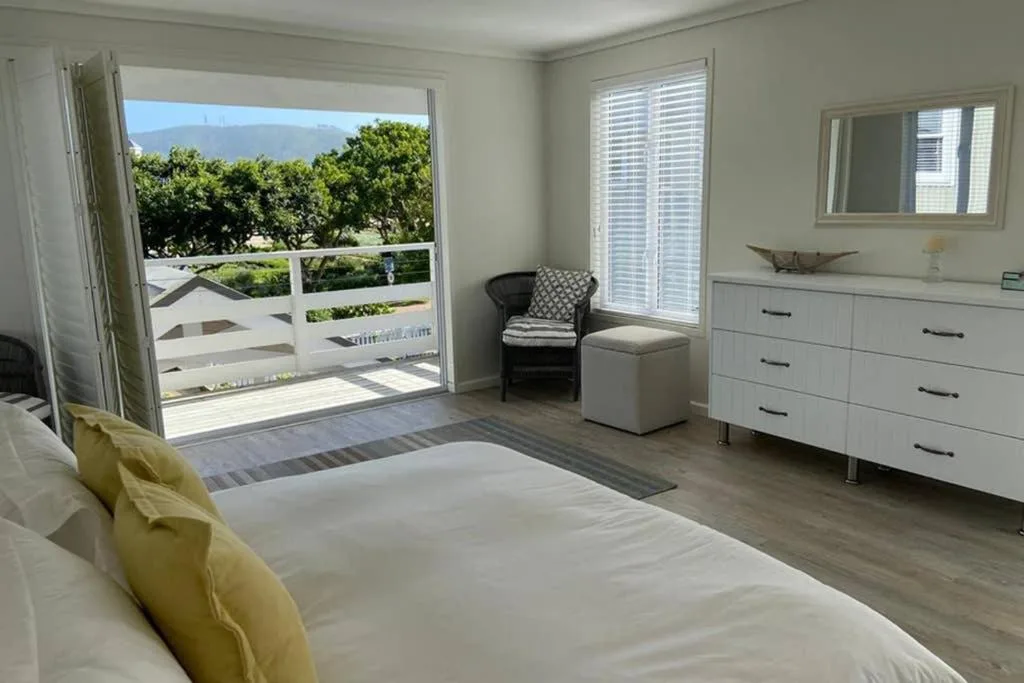 Bright bedroom with queen bed, white dresser, and ocean view deck access