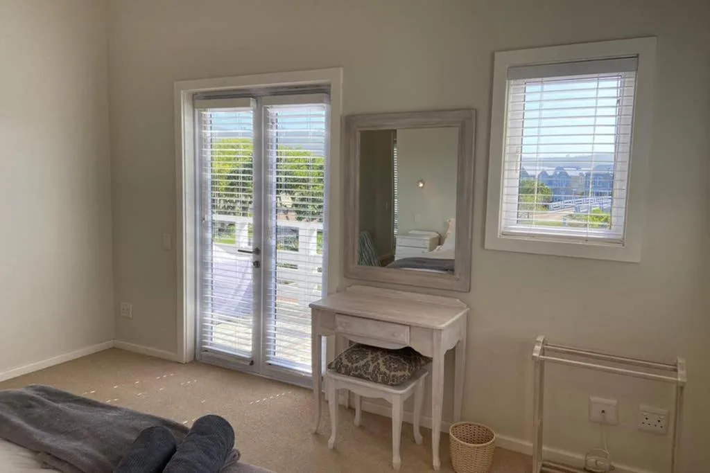 Bright bedroom with vanity desk, sliding doors to deck, garden views