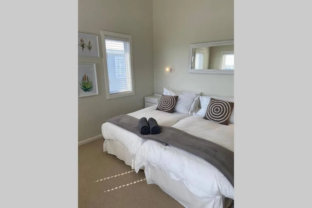 Twin beds with white linens, decorative pillows, and rolled towels in bright room