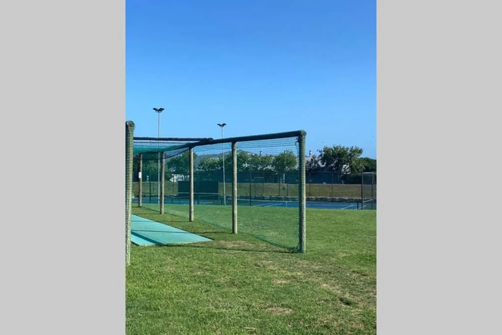 Sports court with net canopy on manicured lawn under clear blue sky