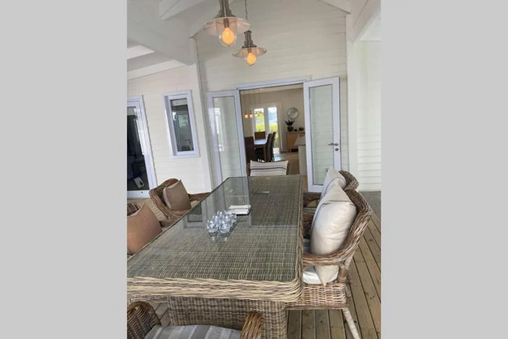 Outdoor deck with wicker seating and dining table overlooking interior spaces