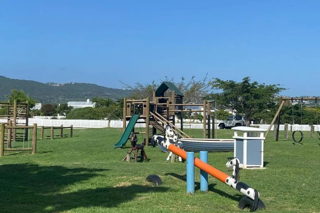 Children's playground equipment and agility course on manicured grass grounds