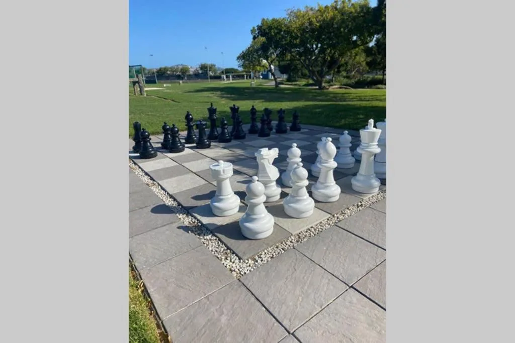 Oversized outdoor chess set on paved deck with garden views beyond