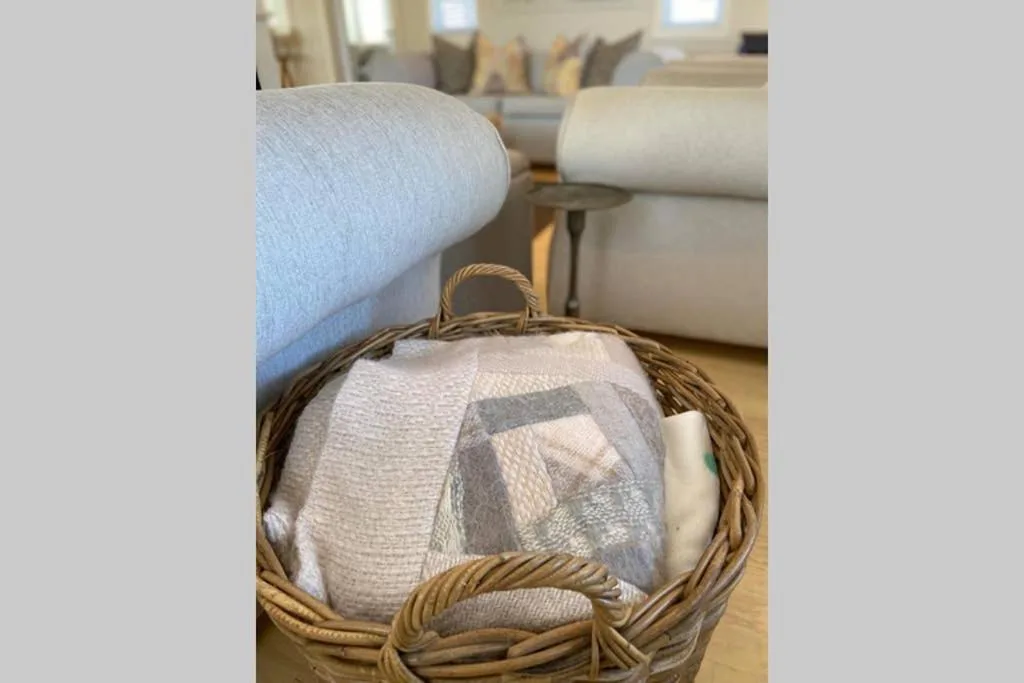 Wicker basket with folded blankets in neutral tones on wooden floor