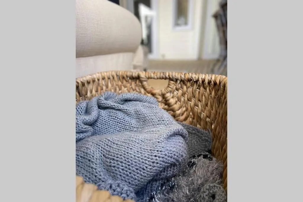 Woven basket with folded blue blankets and cozy textiles