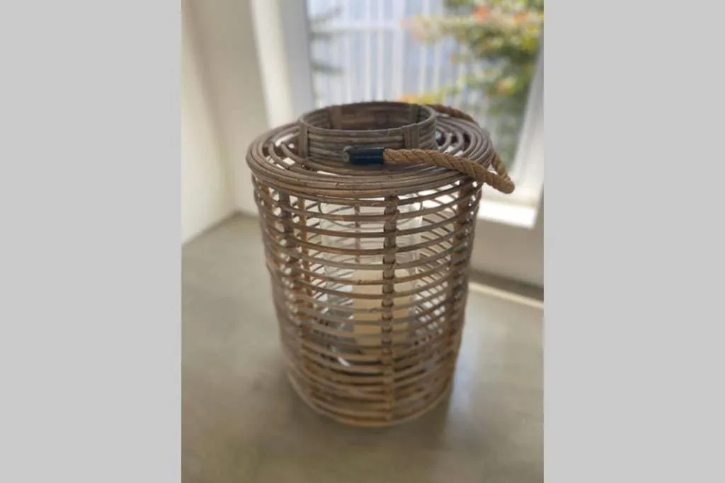 Woven wicker lantern with rope handle on windowsill