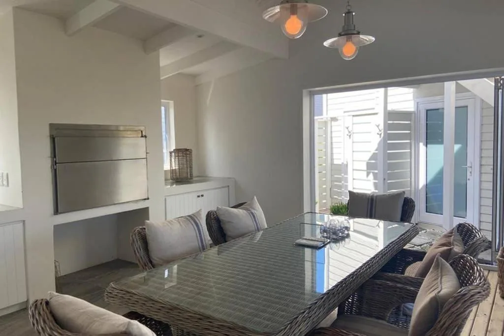 Modern dining area with woven chairs and glass table overlooking deck
