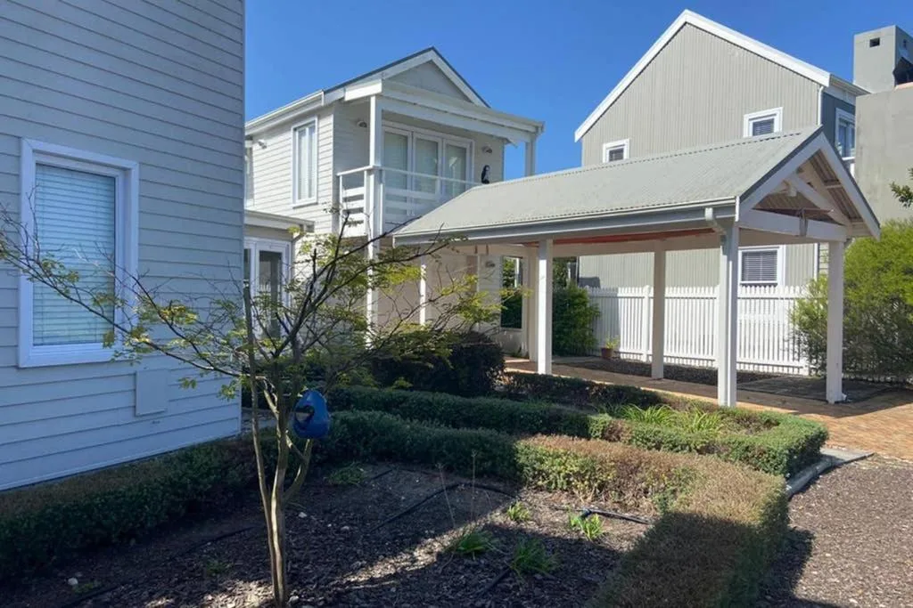 White cottage with covered porch and manicured garden on sunny day