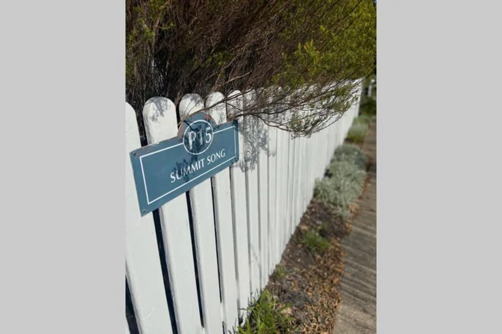 Summit Song property entrance sign on white fence with landscaping