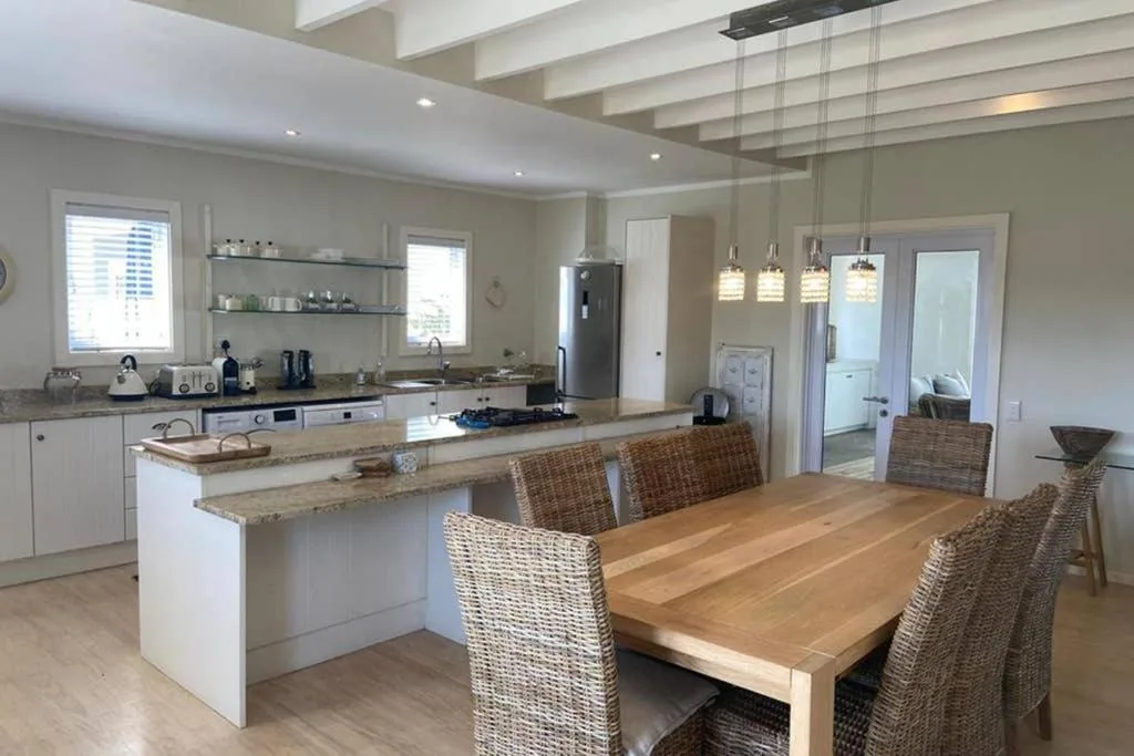 Modern open-plan kitchen with white cabinetry, granite counters, and dining area