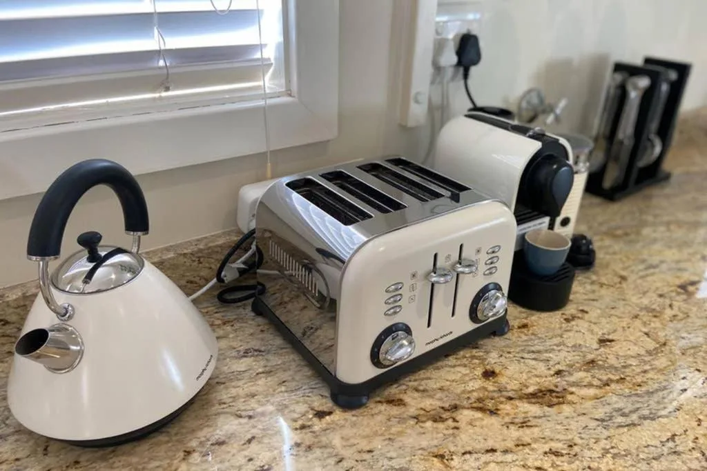 Kitchen counter with white kettle, toaster, and coffee maker appliances