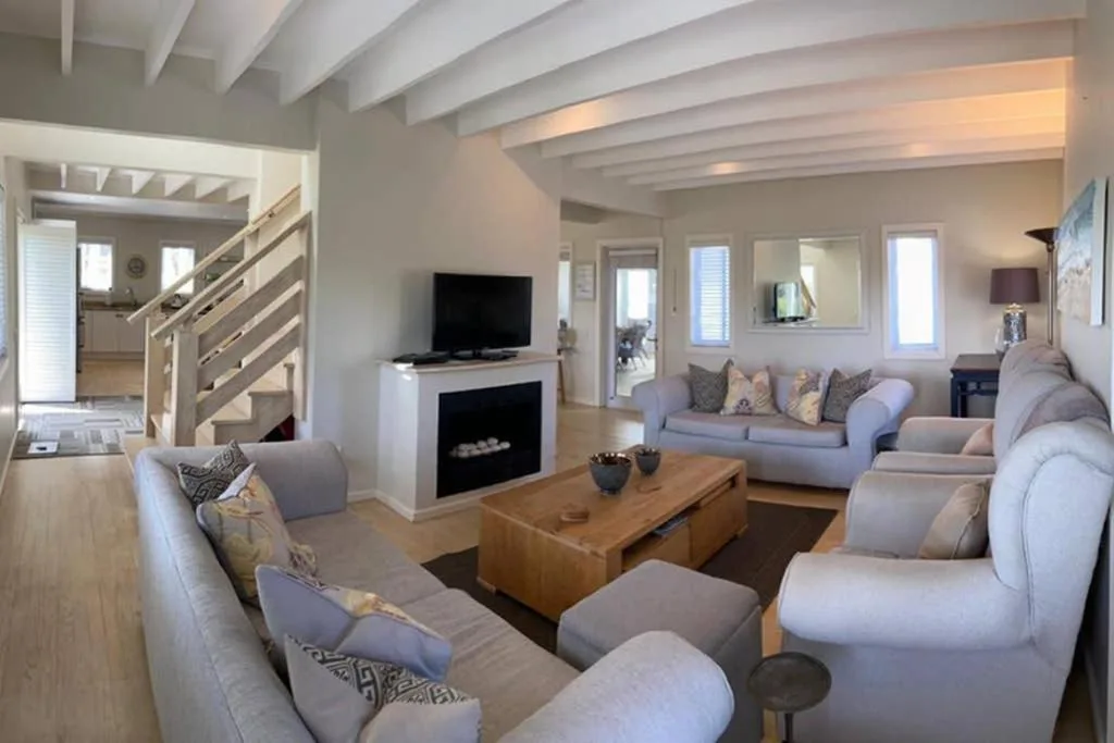 Bright open-plan lounge with grey sofas, fireplace, wooden coffee table