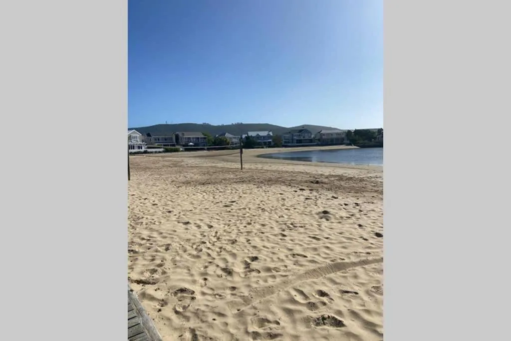 Sandy beach with lagoon water and residential properties on hillside beyond
