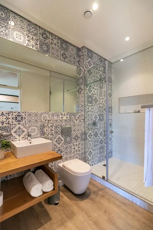 Modern bathroom with patterned tiles, vanity sink, and glass shower enclosure