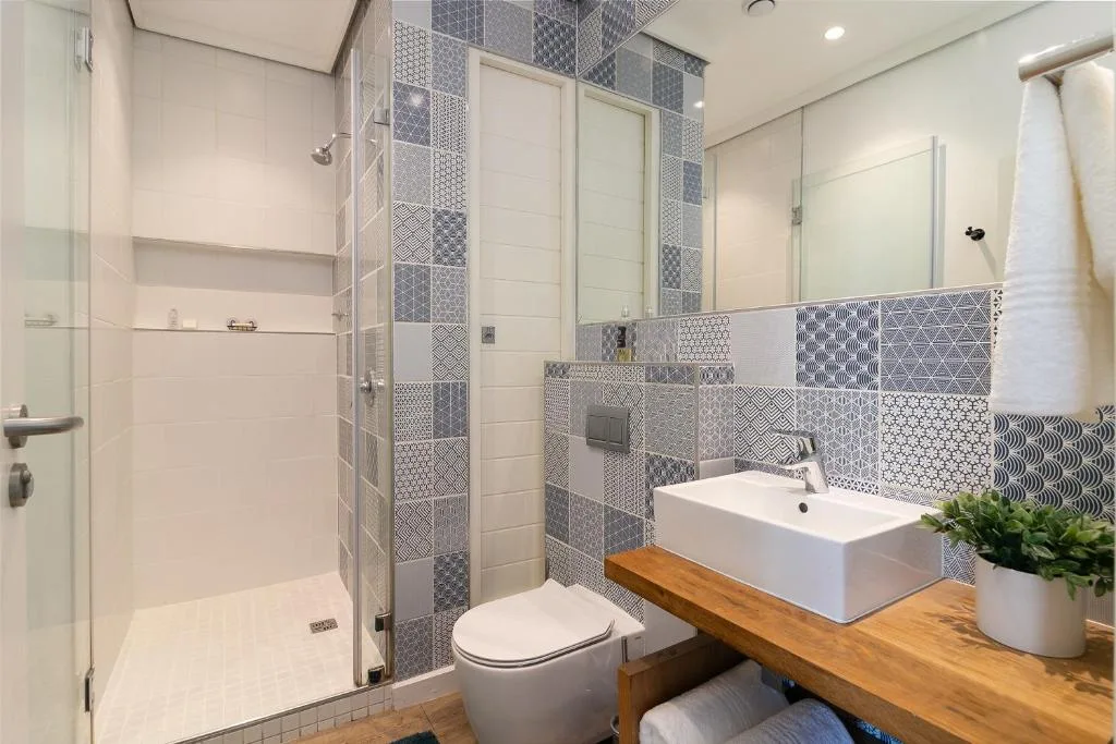 Modern bathroom with walk-in shower, patterned tile backsplash, and wooden vanity