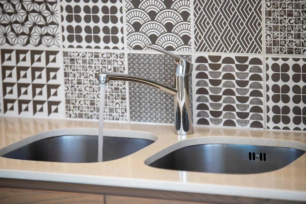 Modern dual sink vanity with geometric patterned tile backsplash and chrome faucet