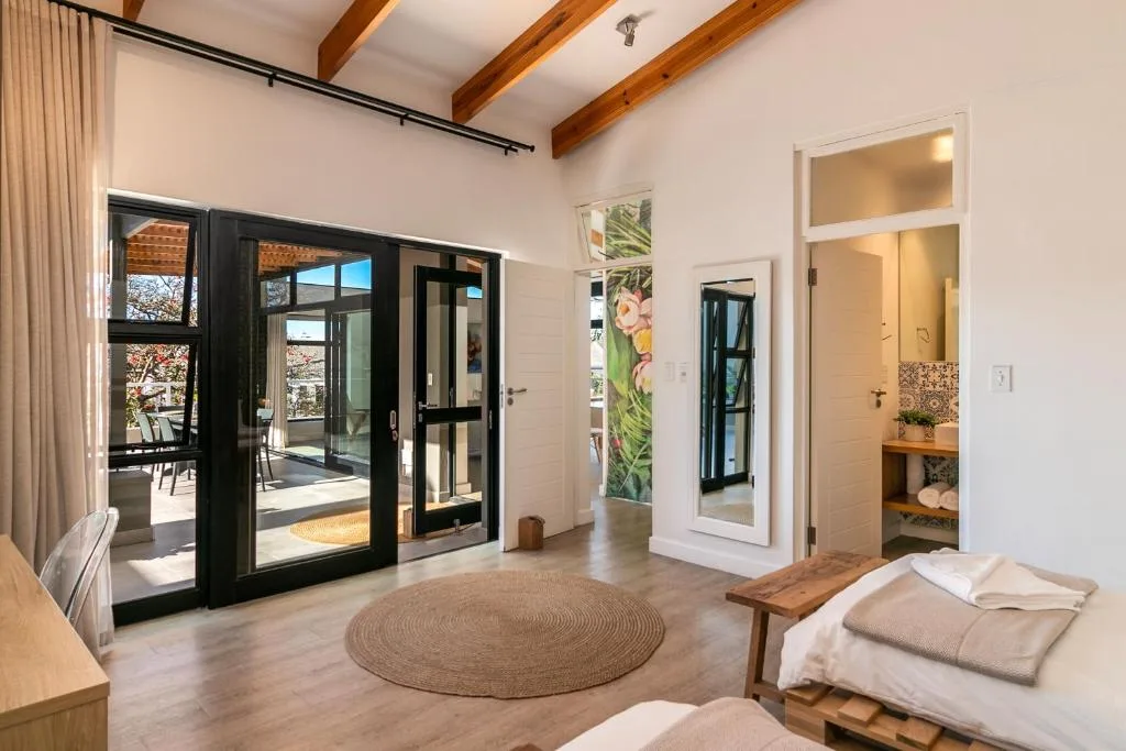 Bright bedroom with wooden beams, deck access, and ensuite bathroom visible