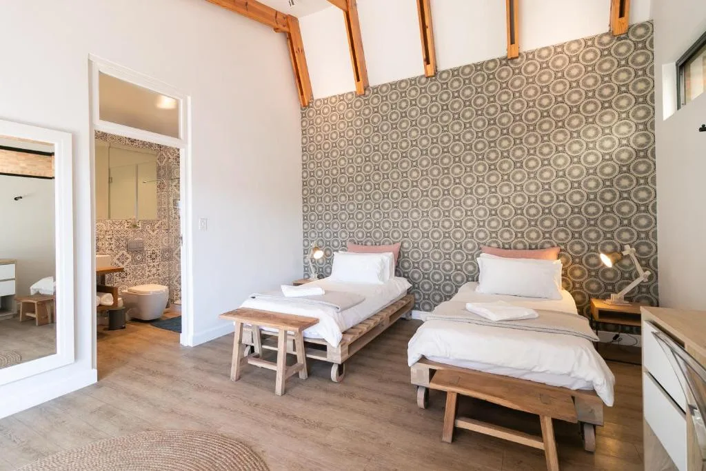 Modern bedroom with two beds, patterned accent wall, and ensuite bathroom visible