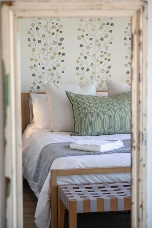 Neatly made bed with green striped pillow and artistic headboard wall art