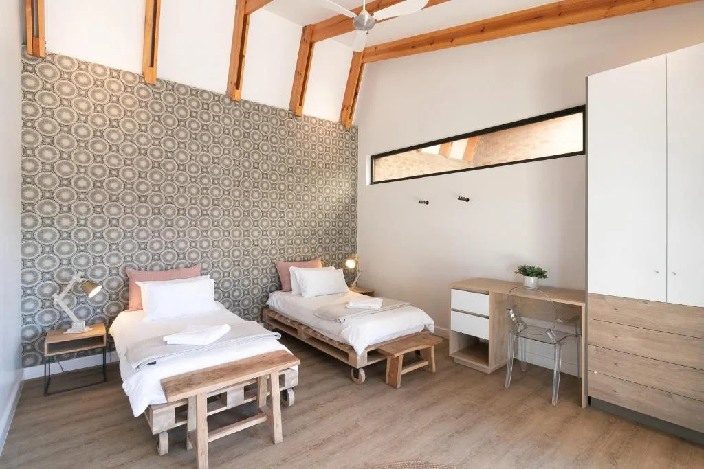 Twin beds in modern bedroom with patterned feature wall and wooden beams