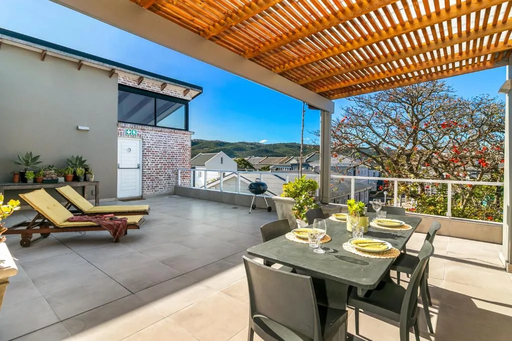 Spacious rooftop deck with dining table, loungers, and mountain views