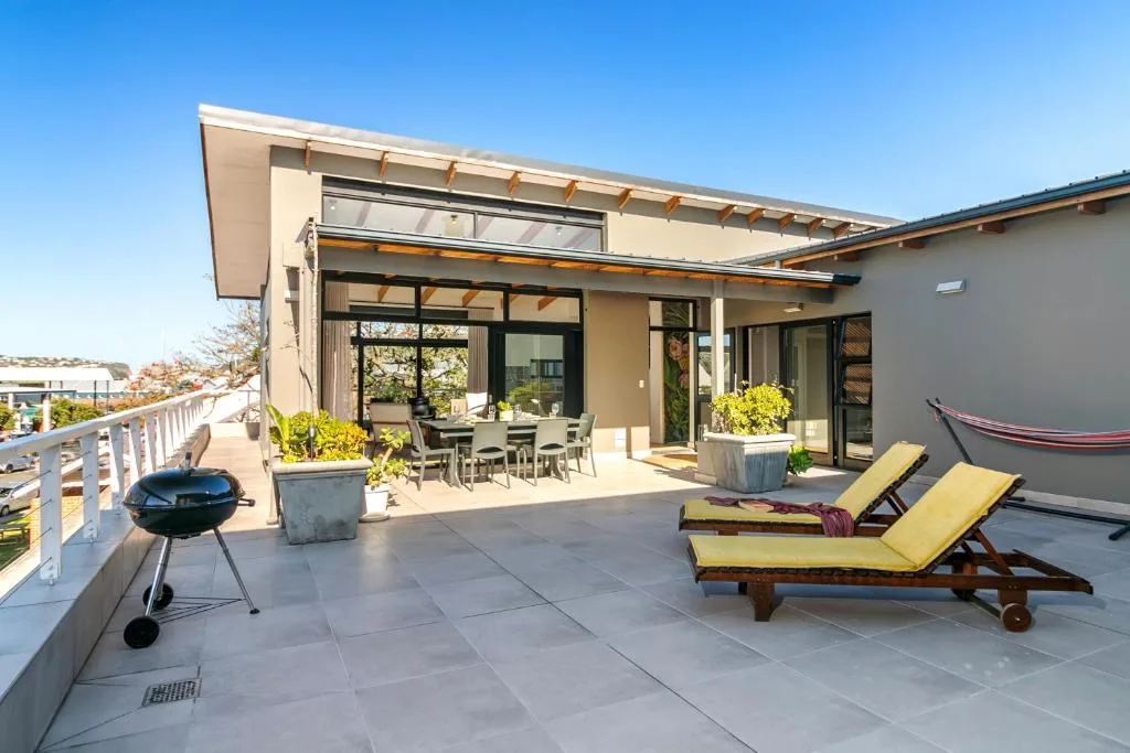 Spacious patio with loungers, braai, and modern architecture overlooking surroundings