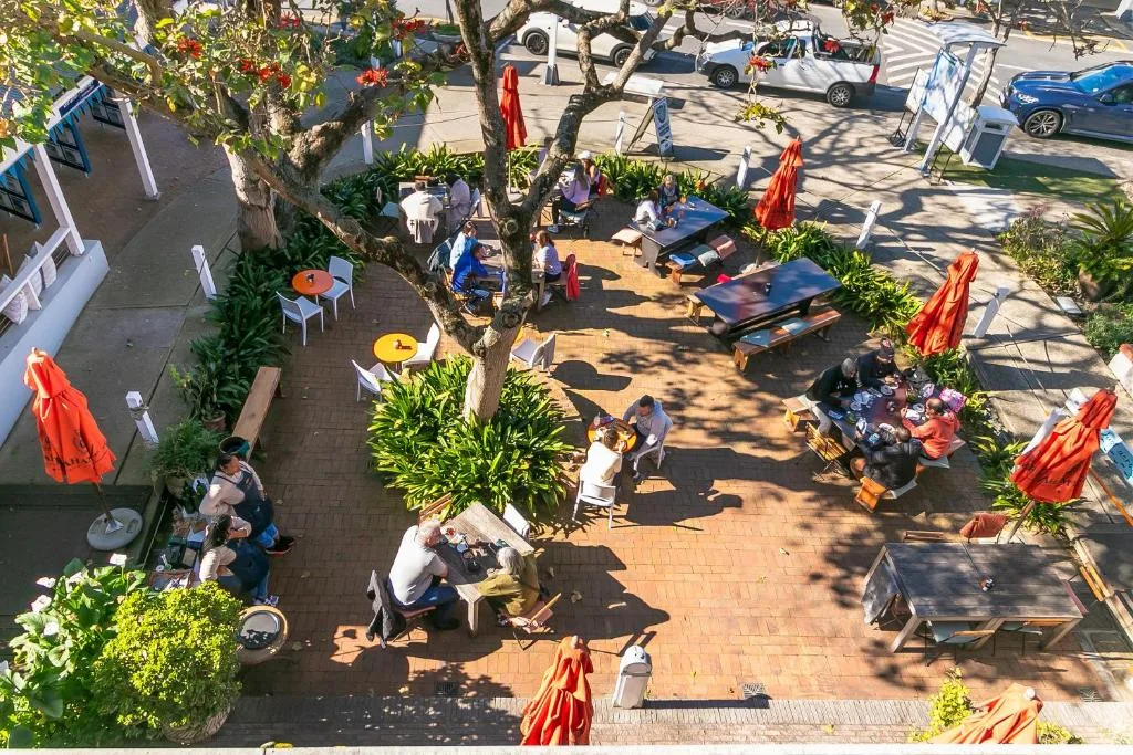 Aerial view of shared courtyard with dining tables, umbrellas, and seating