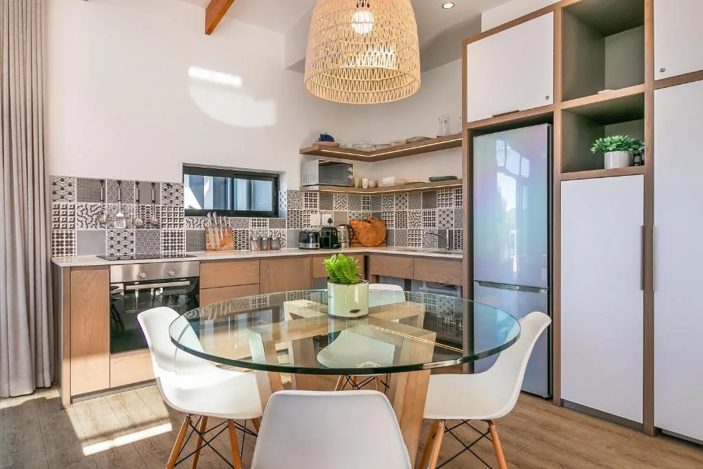 Modern kitchen with patterned backtile, wood cabinetry, and dining table
