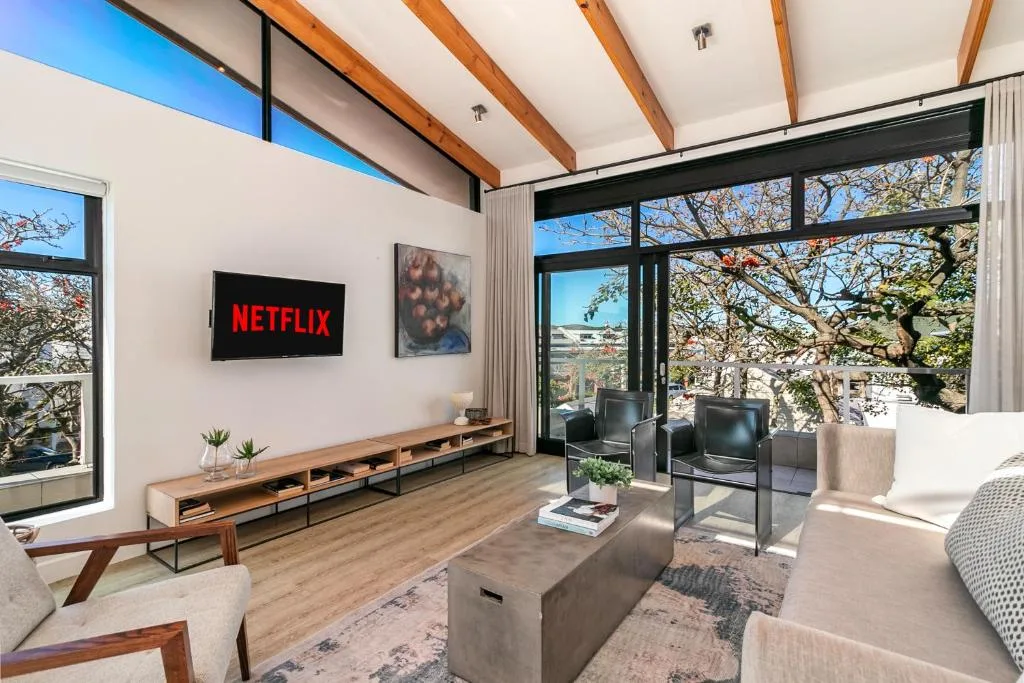 Modern living room with TV, comfortable seating, and large windows overlooking landscape
