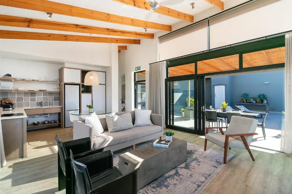 Modern lounge with gray sofa, wooden beams, and open-plan kitchen layout