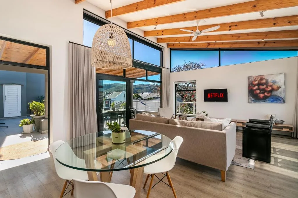 Modern living room with sofa, TV, and large windows overlooking mountains