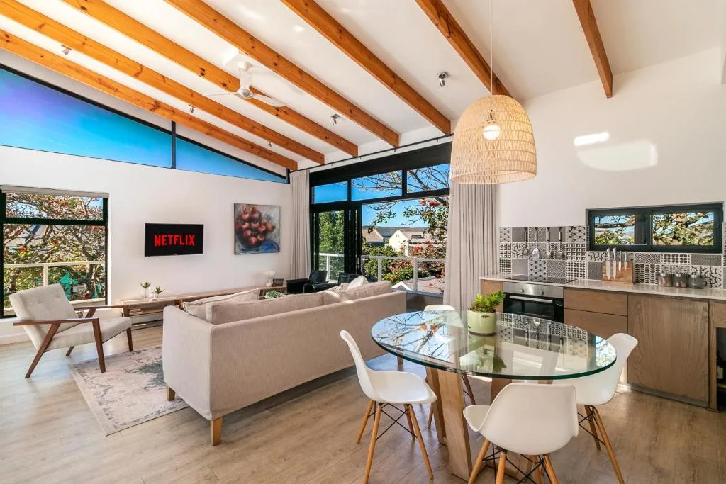 Modern open-plan living room with sofa, dining table, and valley views