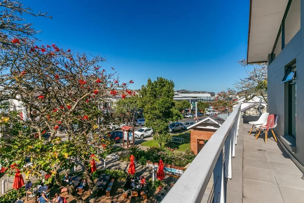 Scenic neighborhood view from balcony with flowering trees and coastal town