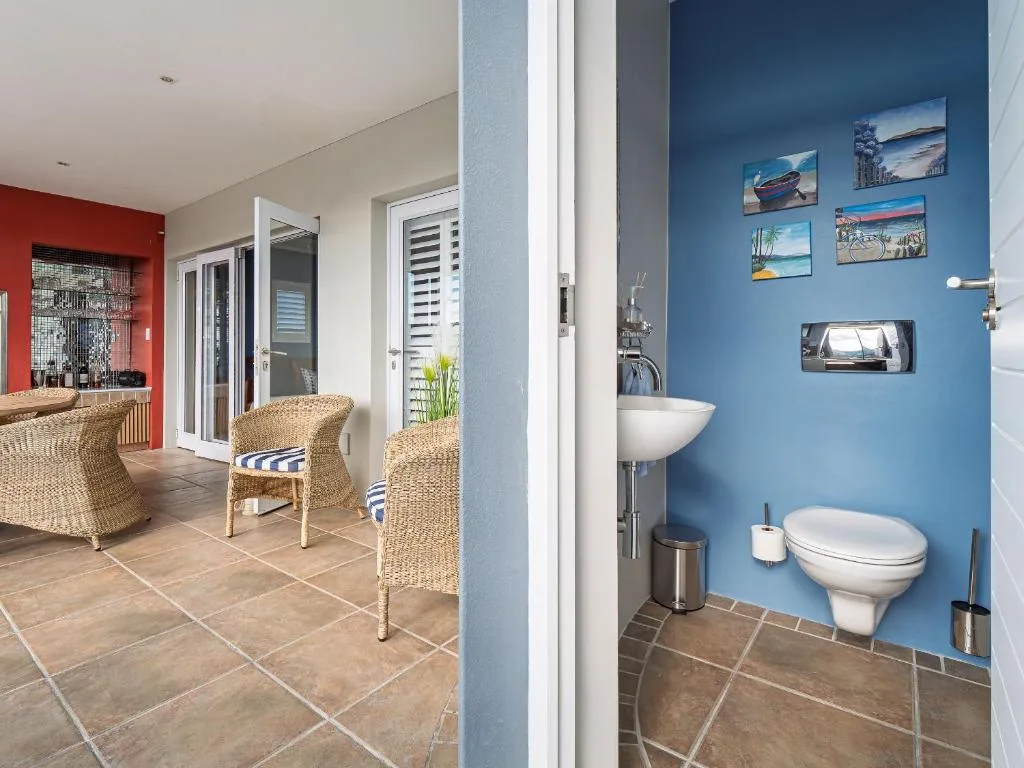 Bright blue bathroom with toilet, sink, and coastal-themed wall art