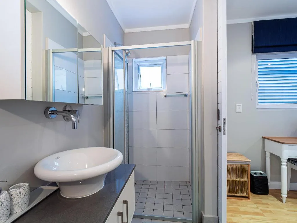 Modern bathroom with round sink, mirror, and glass shower enclosure
