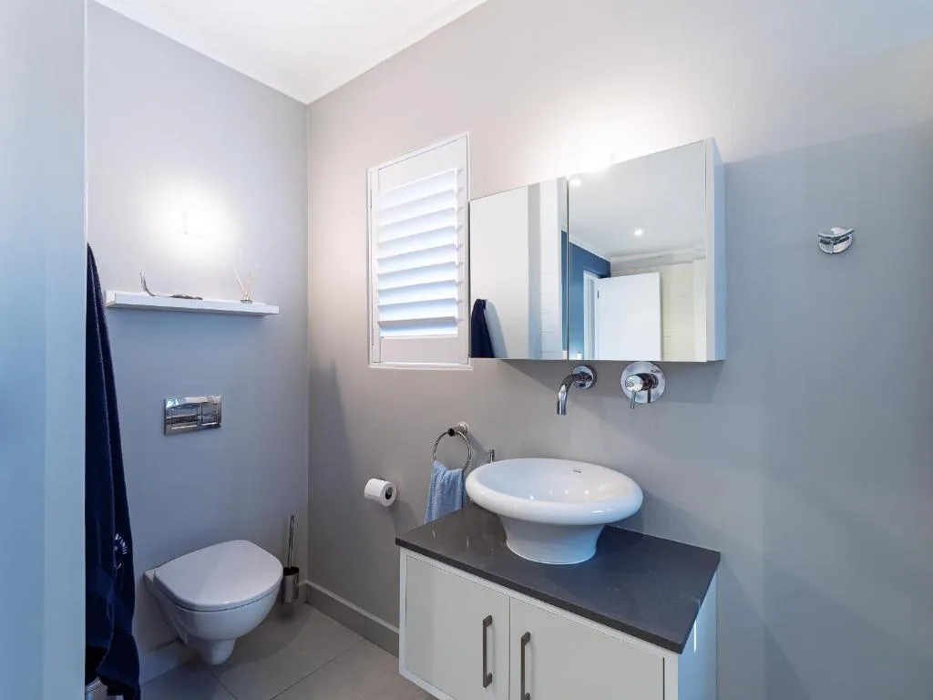 Modern bathroom with round white sink, mirror cabinet, and toilet