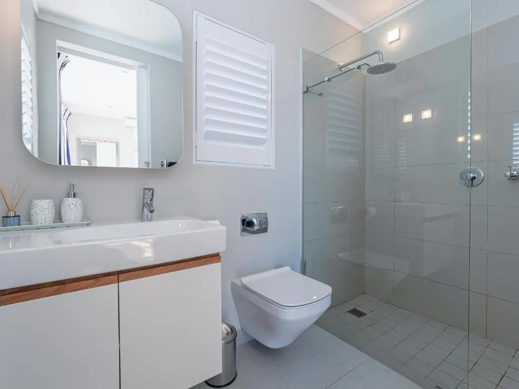 Modern bathroom with walk-in shower, floating vanity, and round mirror