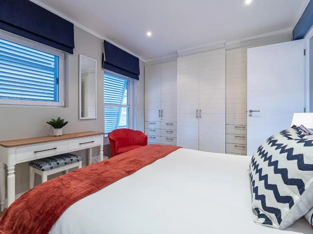 Bright modern bedroom with queen bed, white cabinetry, and red accent chair