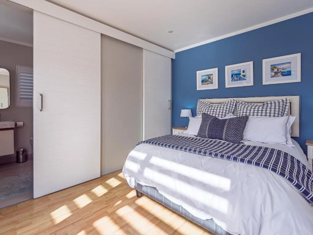 Bright bedroom with blue accent wall, queen bed, and built-in wardrobes