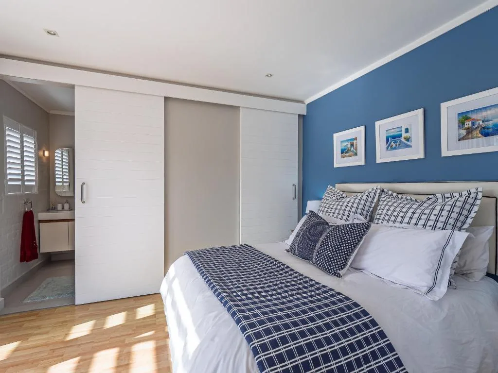 Spacious bedroom with blue accent wall and en-suite bathroom entrance visible