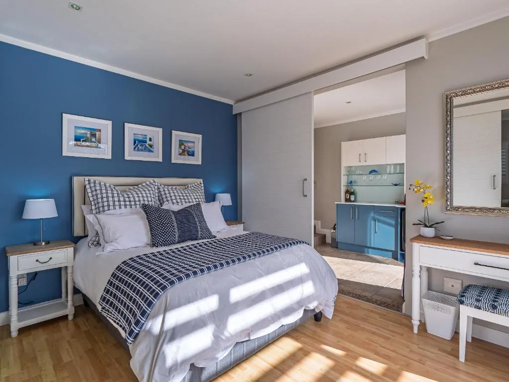 Bright bedroom with blue accent wall, queen bed, and ensuite bathroom visible