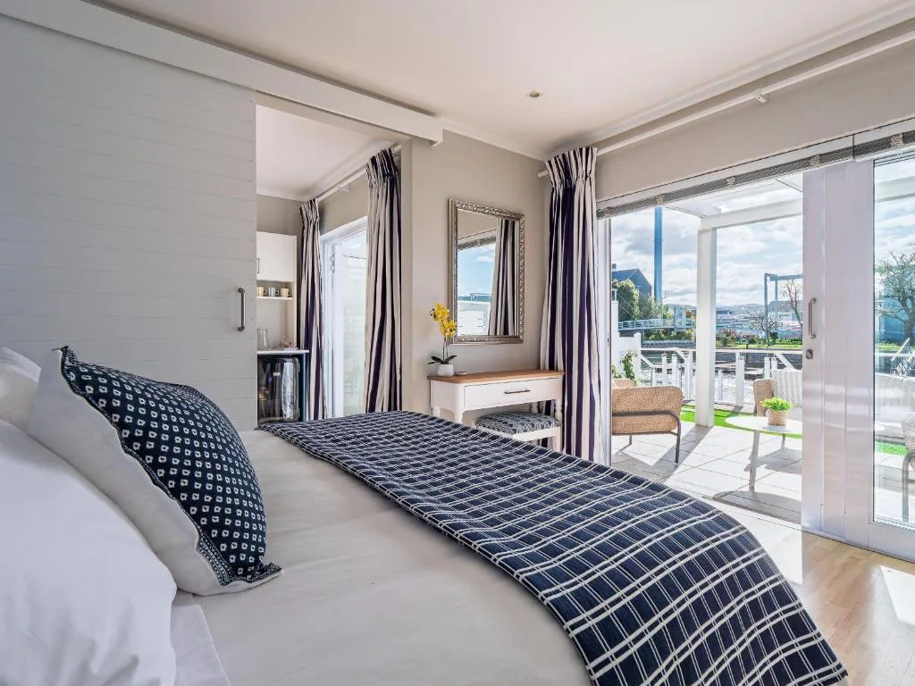 Bright bedroom with double bed, mirrored vanity, and panoramic lagoon views