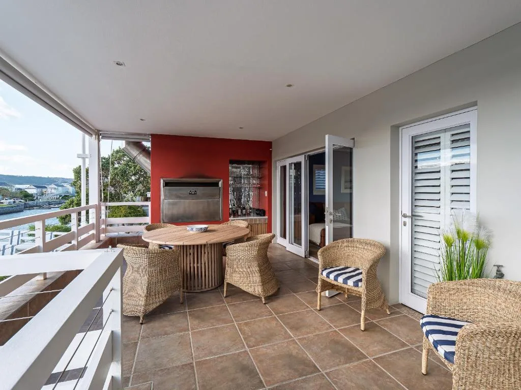 Covered deck with wicker seating, dining table, and water views